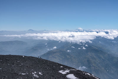 Scenic view of snowcapped mountains against sky with two men tiny people in the foreground