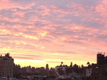 Cityscape against cloudy sky at sunset