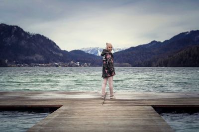 Portrait of woman standing on pier at sea against sky