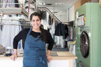 Portrait of smiling mature female dry cleaner standing at laundromat