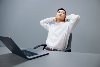 Young woman using laptop while standing against white background