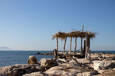 Lifeguard hut on rock at beach against clear sky