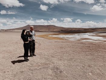 Full length of friends standing on land against sky