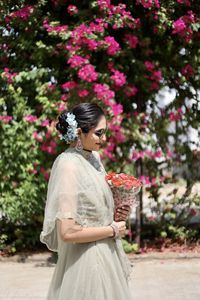 Woman standing by pink flowering plants