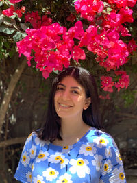 Portrait of smiling young woman standing amidst flowers. showing happiness and hope