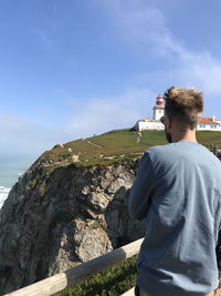 Rear view of man looking at sea against sky