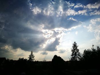 Low angle view of silhouette trees against cloudy sky