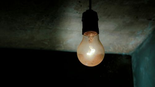 Close-up of illuminated light bulb hanging on ceiling