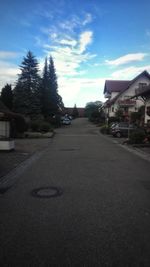 Road by houses against sky