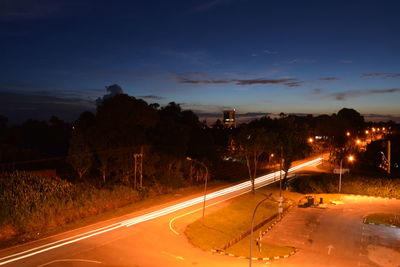 Light trails on road against sky at night