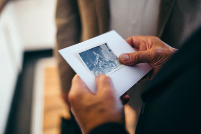 Cropped hands of senior man holding photograph