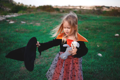 Full length of girl holding camera on field