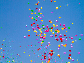 Low angle view of balloons flying against blue sky