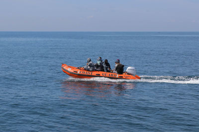 People on boat in sea against sky