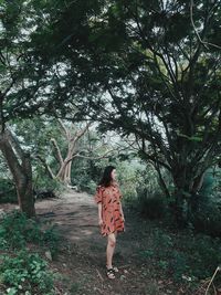 Woman standing by tree against plants