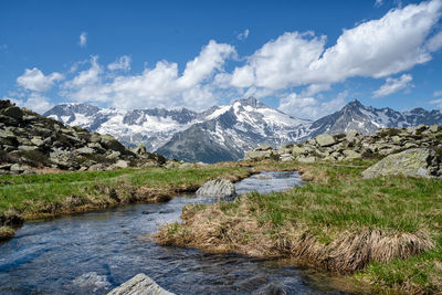 Scenic view along the creek to snowcapped mountains against sky