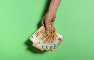 High angle view of hand holding paper against green background