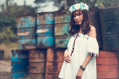 Fashionable woman standing against old containers on field