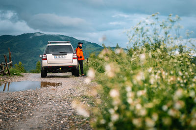 Car and man on mountain road against sky