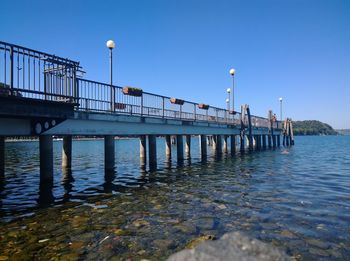 Pier over river against clear blue sky