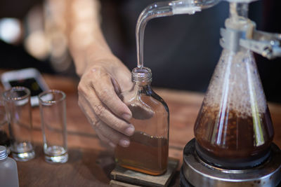 Close-up of hand holding glass bottle on table