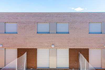 Exterior view of modern semi-detached townhouses with brick facade. sunny day