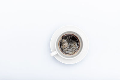 White cup with saucer and coffee on a white background with copyspace