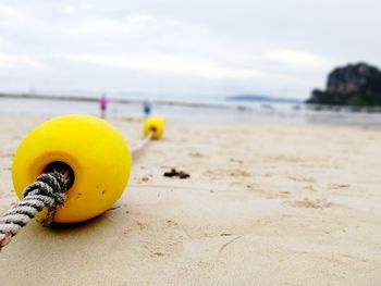 Close-up of yellow rope on beach against sky