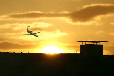 Low angle view of silhouette airplane flying against sky during sunset