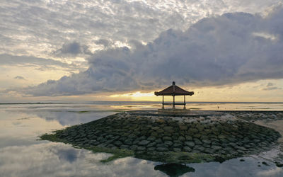Lifeguard hut on beach against sky during sunset