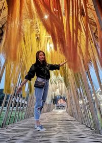 Full length portrait of woman standing on footpath