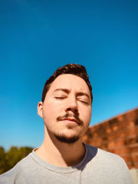 Portrait of young man against clear blue sky