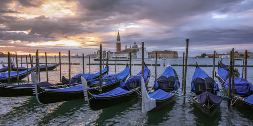 Boats moored in canal at sunset