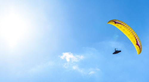 Low angle view of paragliding against blue sky