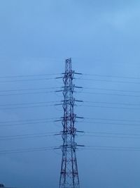 Low angle view of electricity pylon against blue sky