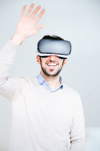 Portrait of man wearing virtual reality simulator against white background