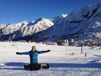 Man kneeling against snowcapped mountains