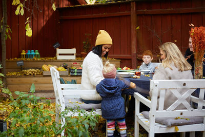 Smiling female looking at girl while sitting by table for garden party