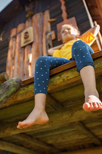 Low section of woman sitting on wooden wall