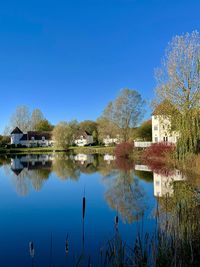 Reflection of building in lake against clear blue sky