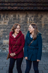 Cheerful sisters standing against stone wall