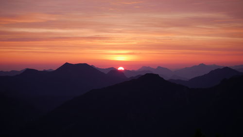 Scenic view of silhouette mountains against orange sky