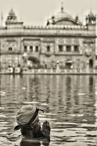 Rear view of man photographing water against sky