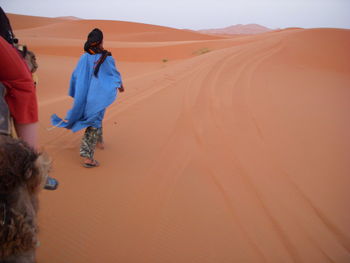 Rear view full length of woman walking on sand dunes at desert