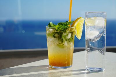 Close-up of drinks on table against sea