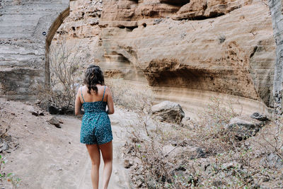 Rear view of woman standing on rock