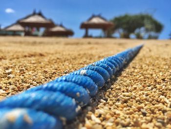 Close-up of blue rope at beach by huts against sky