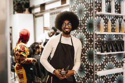 Portrait of smiling male barber standing in hair salon