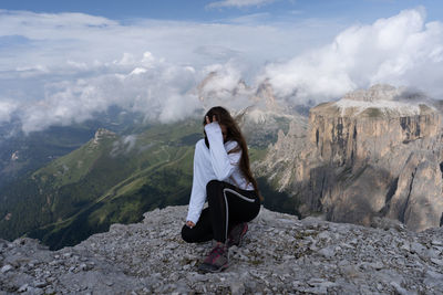 Man sitting on rock against mountains