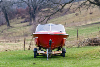 Red motorboat on trailer in farm yard